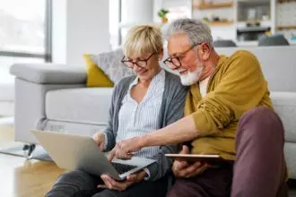 Cheerful senior couple using technology devices and having fun at home