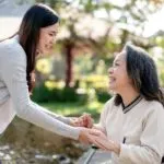Elderly grandmother in wheelchair with daughter smiling enjoying at the garden in the morning