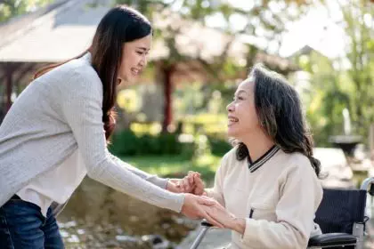 Elderly grandmother in wheelchair with daughter smiling enjoying at the garden in the morning