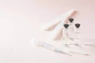 Vaccination and Immunization. Open syringe in front of glass vials with vaccine and clean syringes